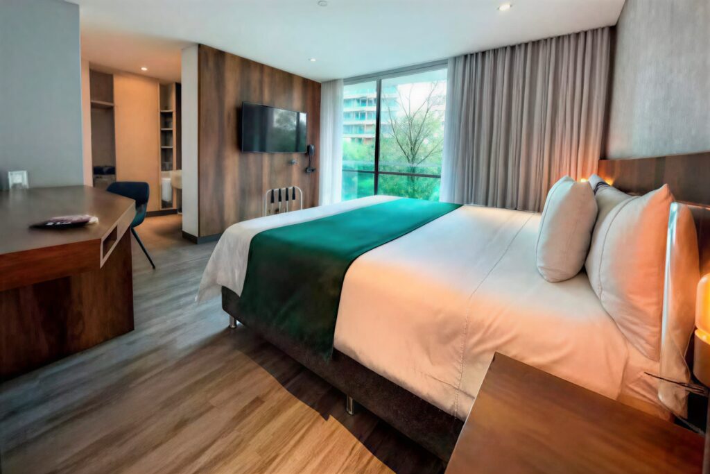 Modern accommodations in Medellín: Luxury room in El Poblado at Café Hotel, featuring city views and a workspace.