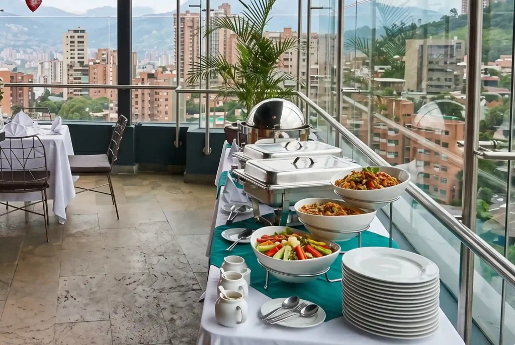 Buffet de desayuno con verduras y platos calientes en terraza de Café Hotel Medellín, nutrición para atletas en El Poblado