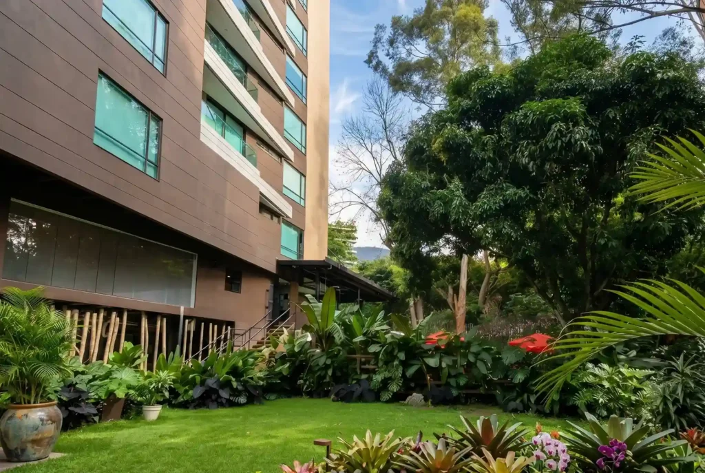 Jardín tropical con bromelias, palmas y bambú junto a fachada de Café Hotel Medellín, arquitectura biofílica en El Poblado
