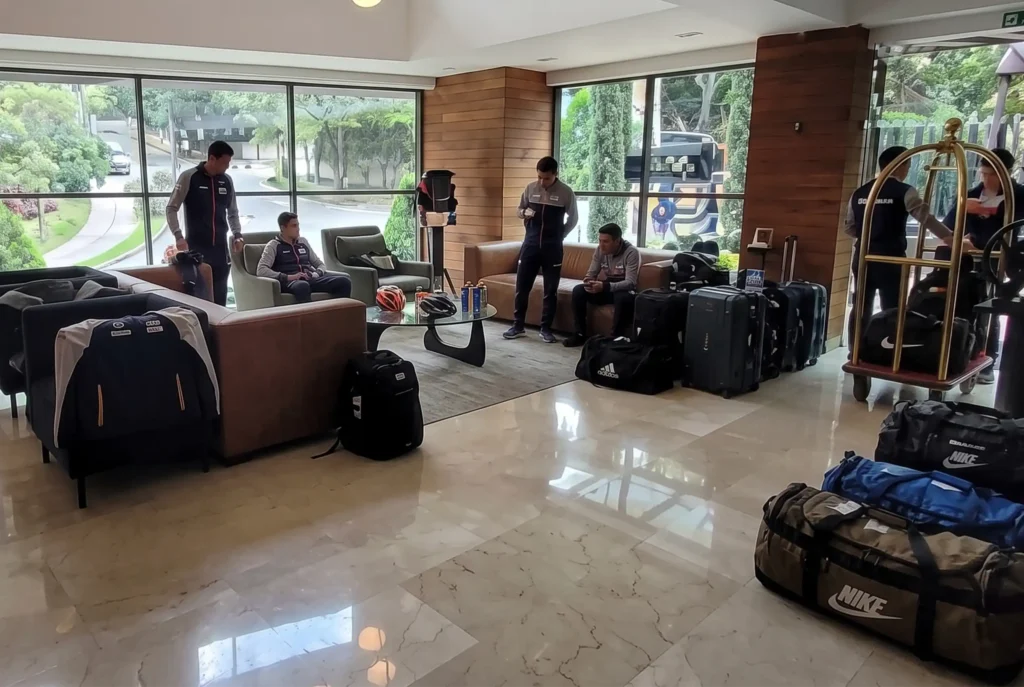 Equipo deportivo con equipaje en el amplio lobby de Café Hotel Medellín durante su registro.