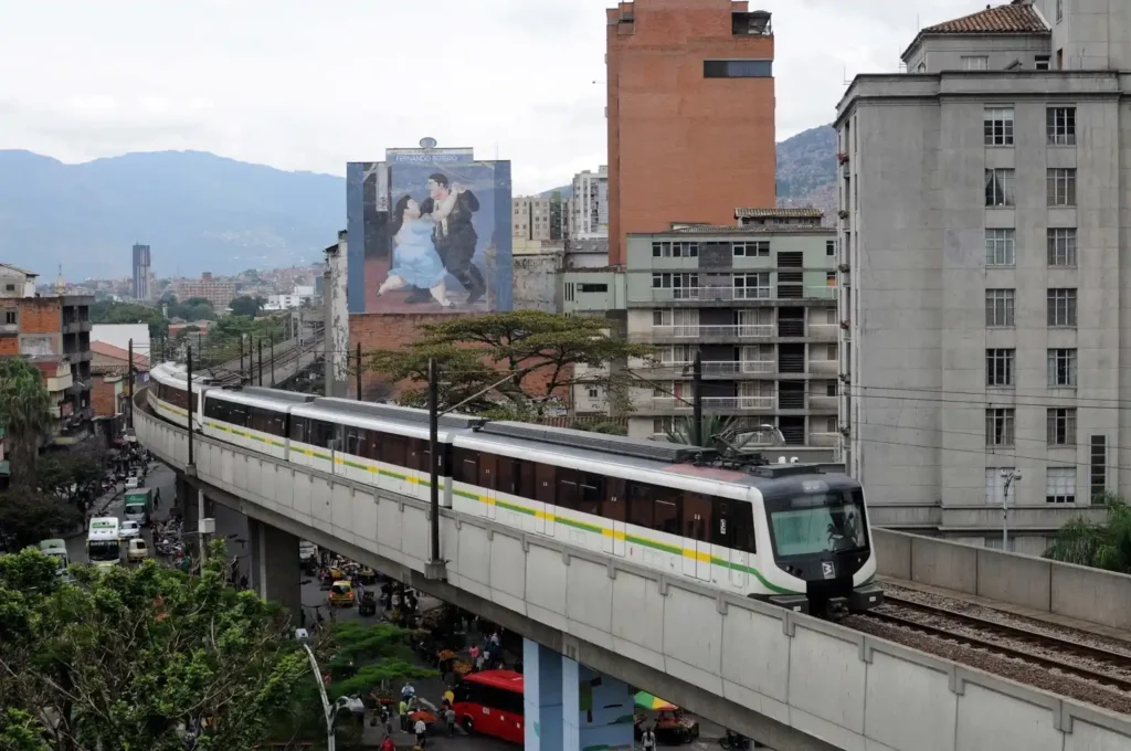 Metro de Medellin en viaducto con mural de Fernando Botero al fondo.