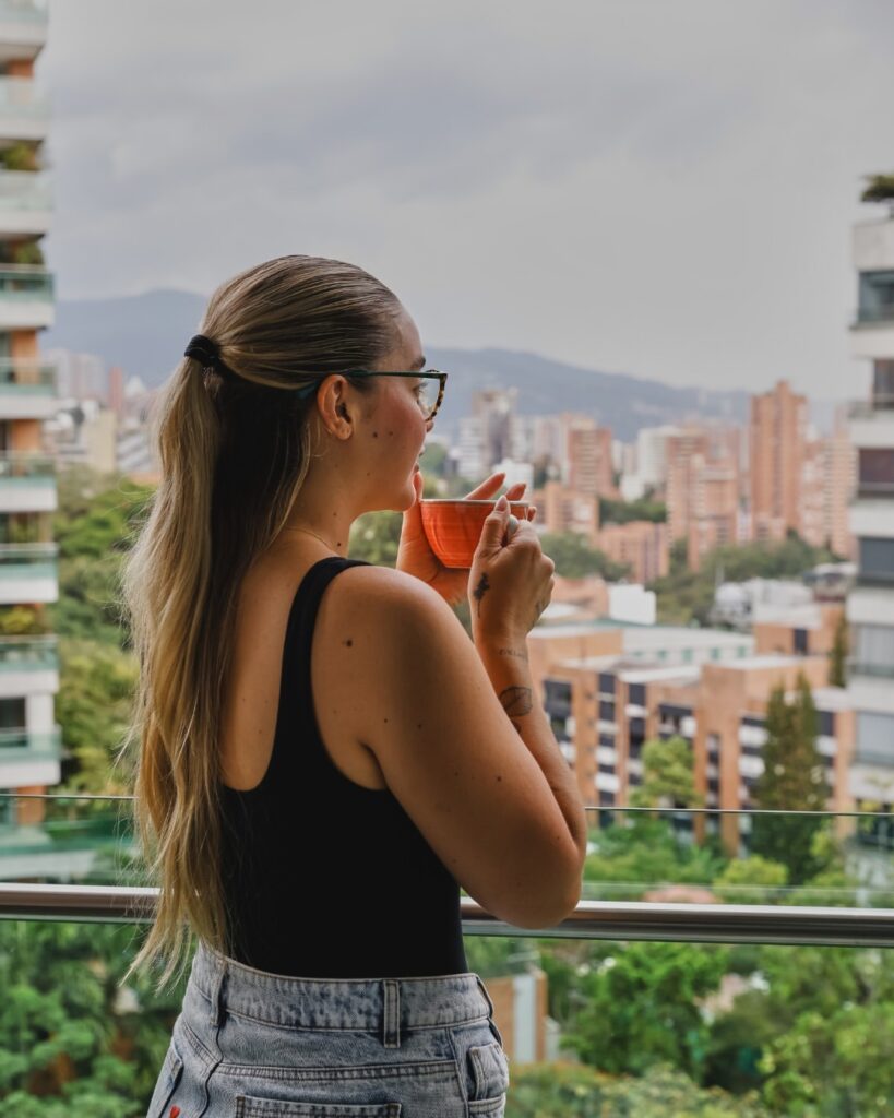 A guest drinking coffee on a terrace overlooking the Medellín skyline
