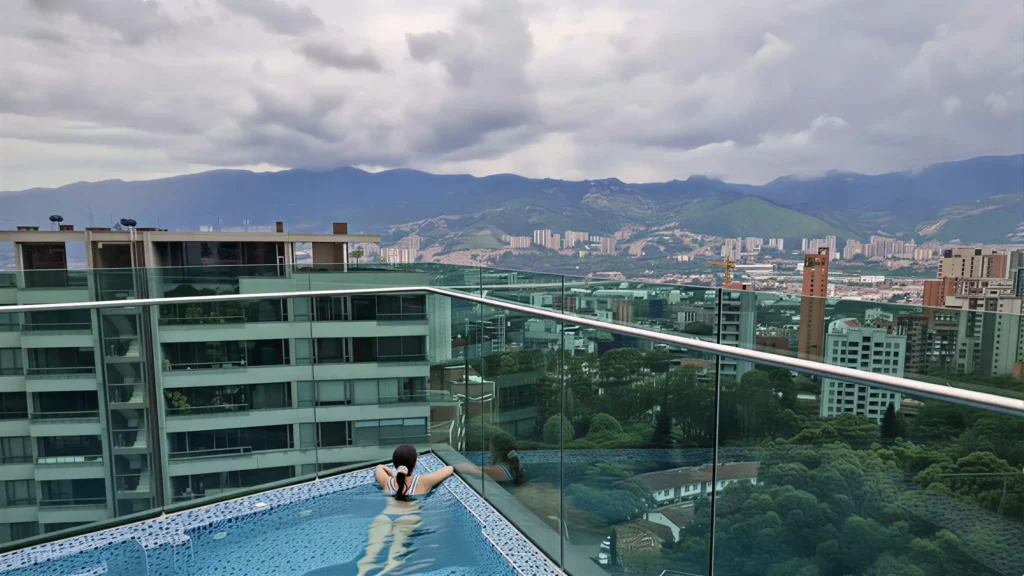 Huésped en piscina del rooftop de Café Hotel con vista panorámica de Medellín.